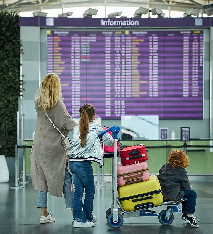 Family checking airport departure board while traveling for Passover